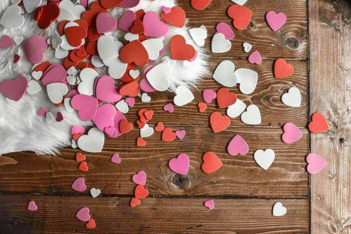 Red, pink and white hearts in various shapes scatterd over a wooden floor